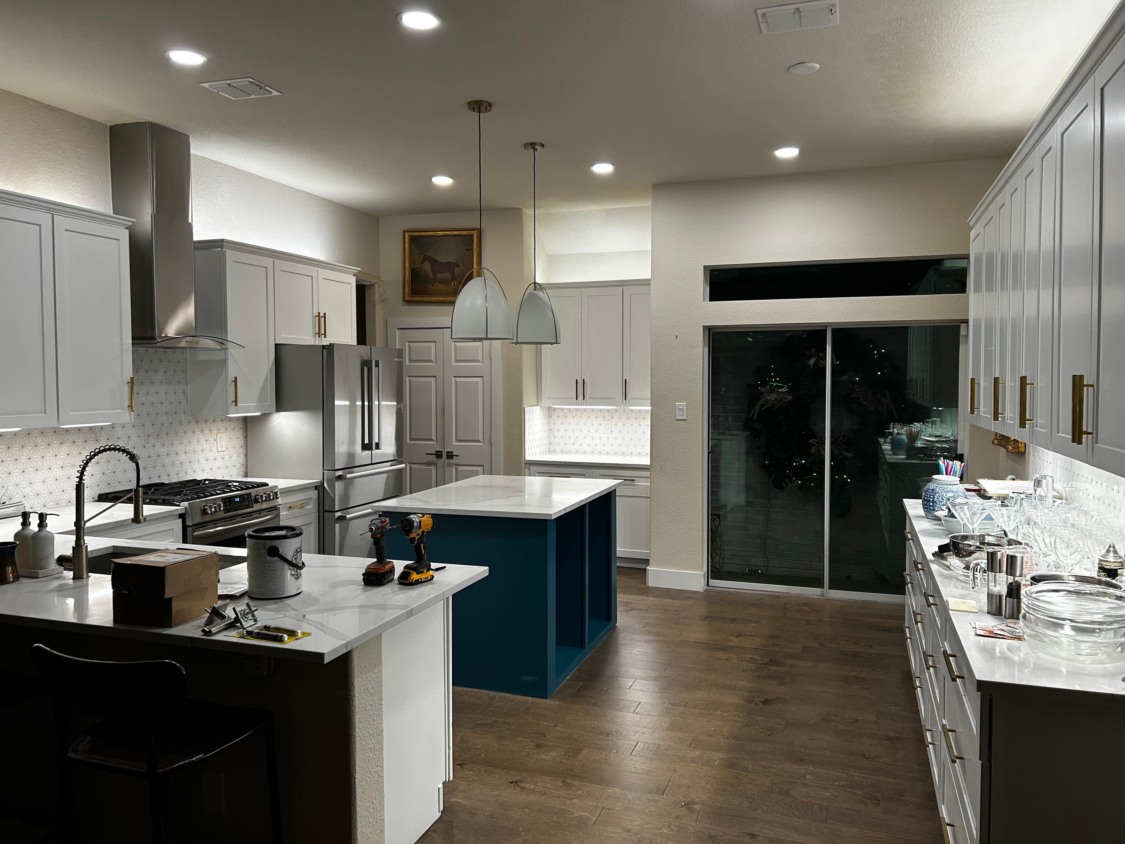White kitchen remodel with a blue island, waterfall quartz countertop, brass hardware, and a wood-look plank ceiling