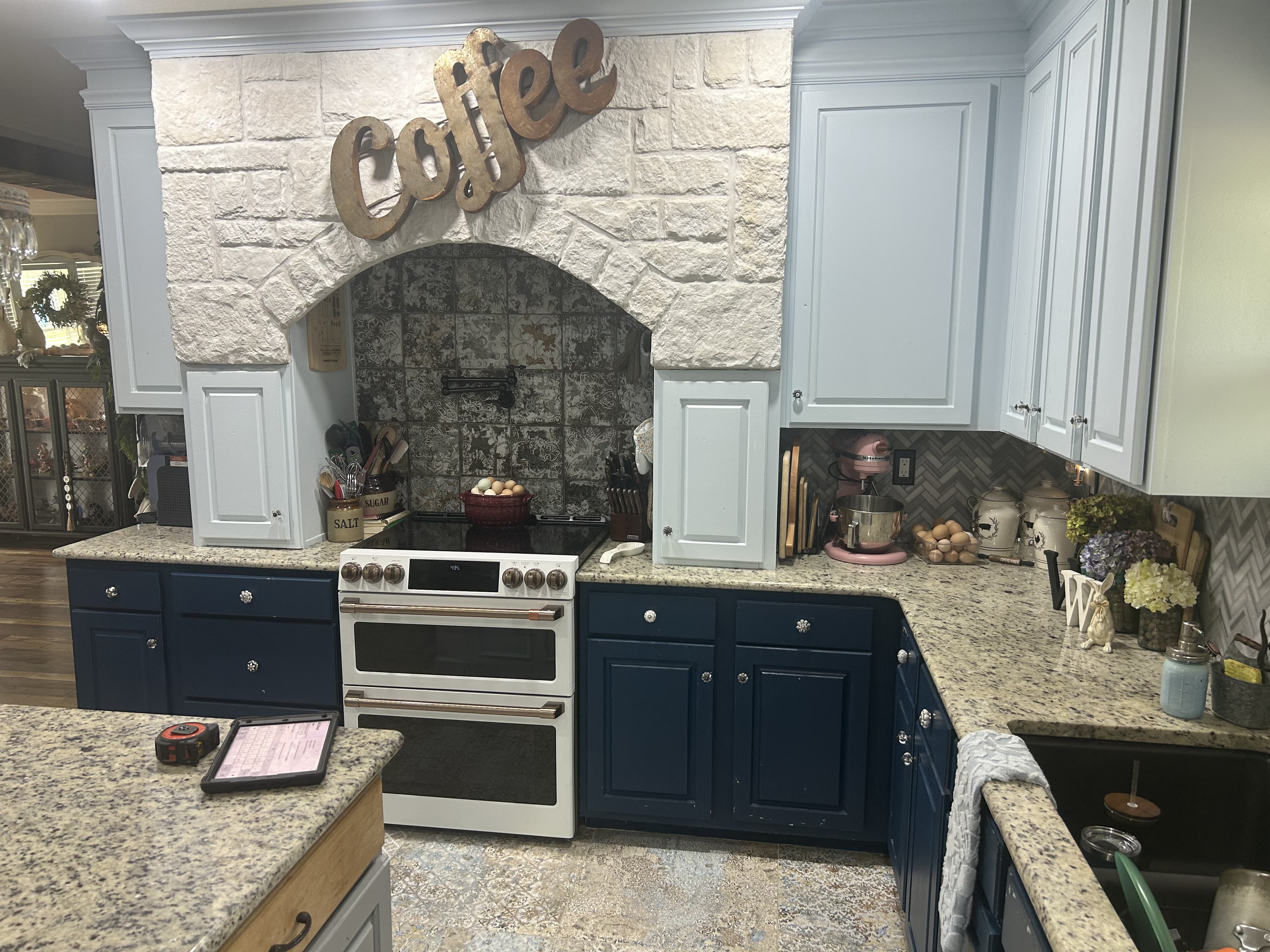 Farmhouse kitchen with a stone-arch range wall, white and navy cabinets, and a white double-oven range