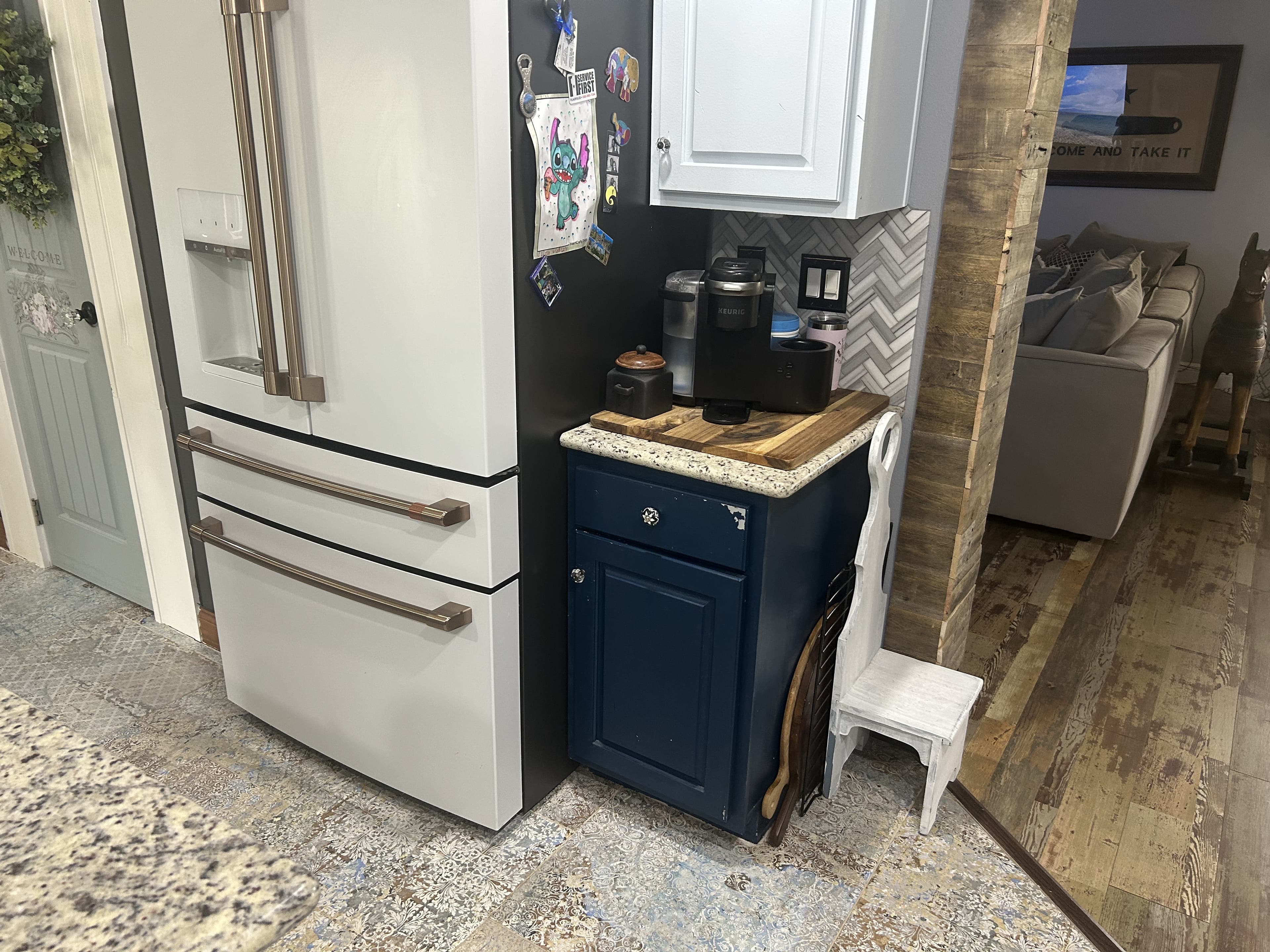 Farmhouse kitchen coffee bar with a navy cabinet, granite top, reclaimed-wood accent wall, and a white French-door refrigerator