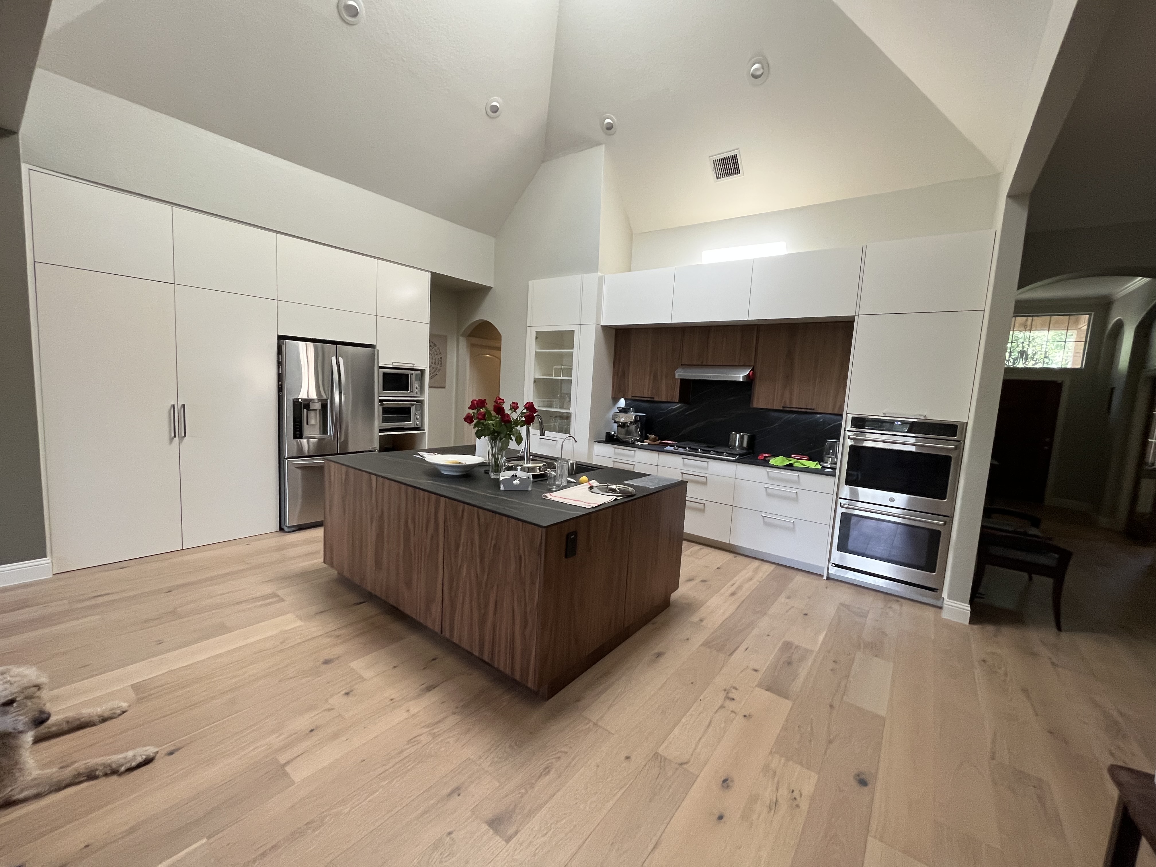 Bright modern Westlake Hills kitchen with vaulted ceiling, white cabinetry, walnut wood island, and light oak hardwood floors