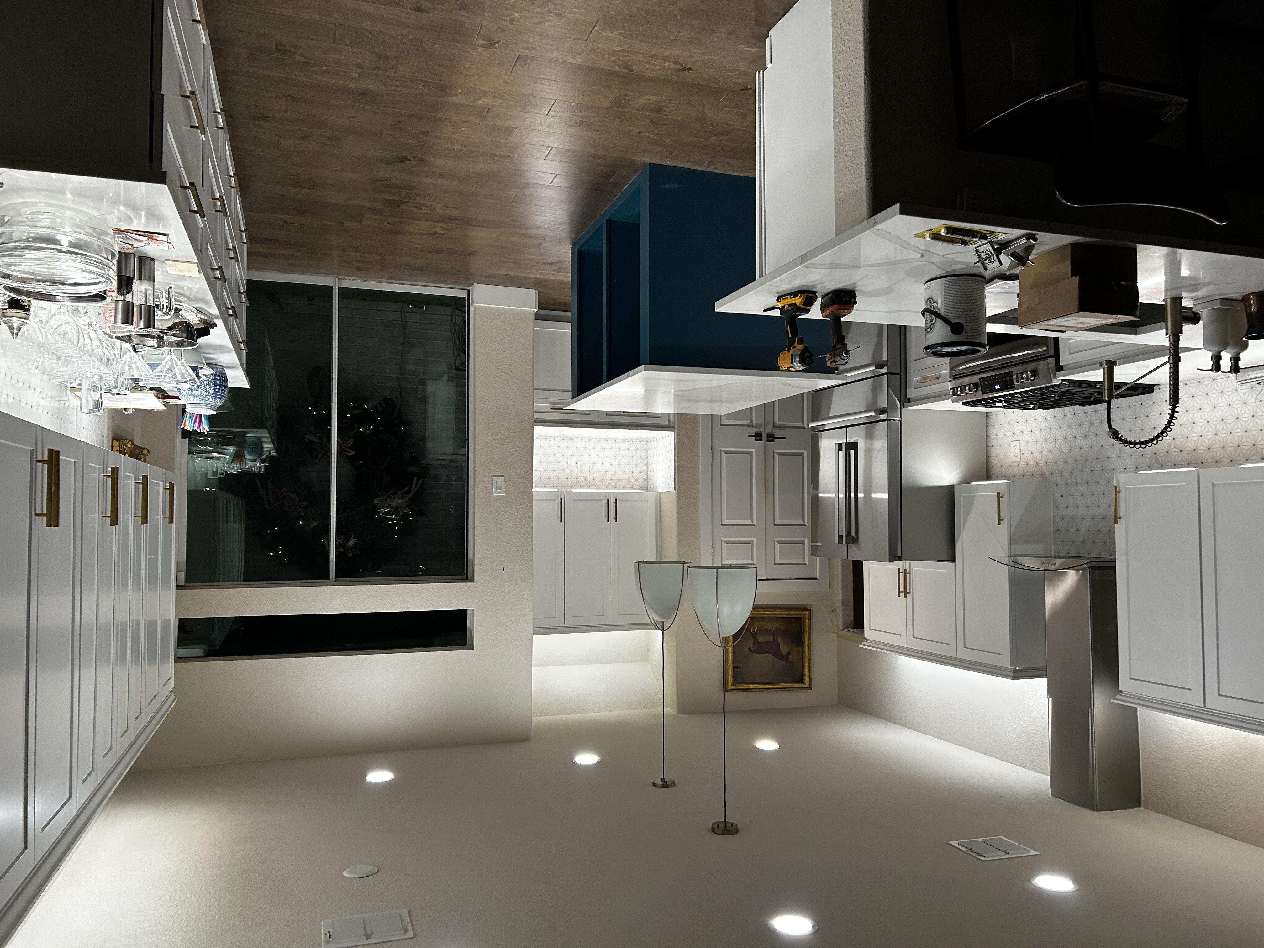 White kitchen remodel with a blue island, waterfall quartz countertop, brass hardware, and a wood-look plank ceiling